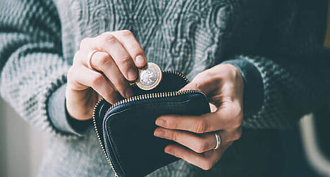 pale skinned woman putting money into a purse