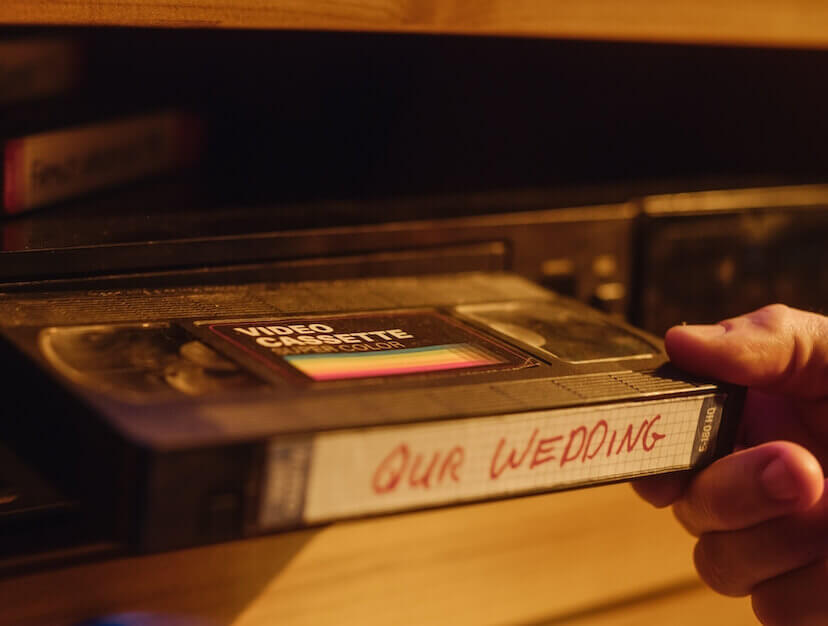 home movie VHS A video tape is being inserted into a VHS player with the text 'Our wedding' on the video label.